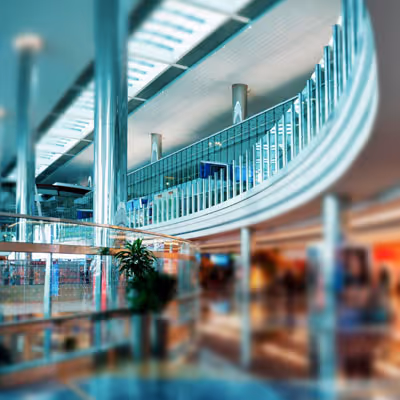 A modern, large indoor shopping mall with glass railings and metal columns.
